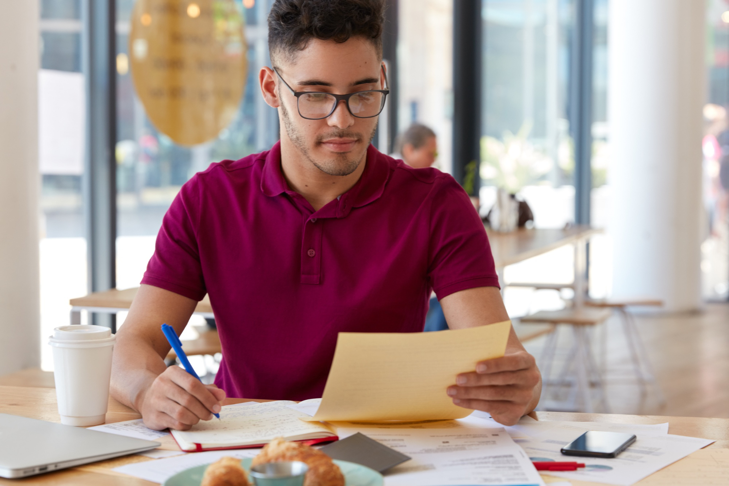 Man holds paper and makes notes