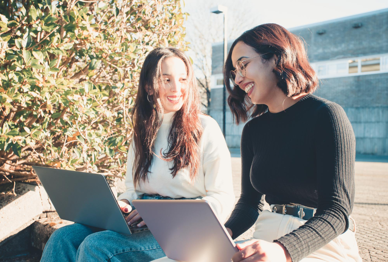 Two young girls with laptops are smiling